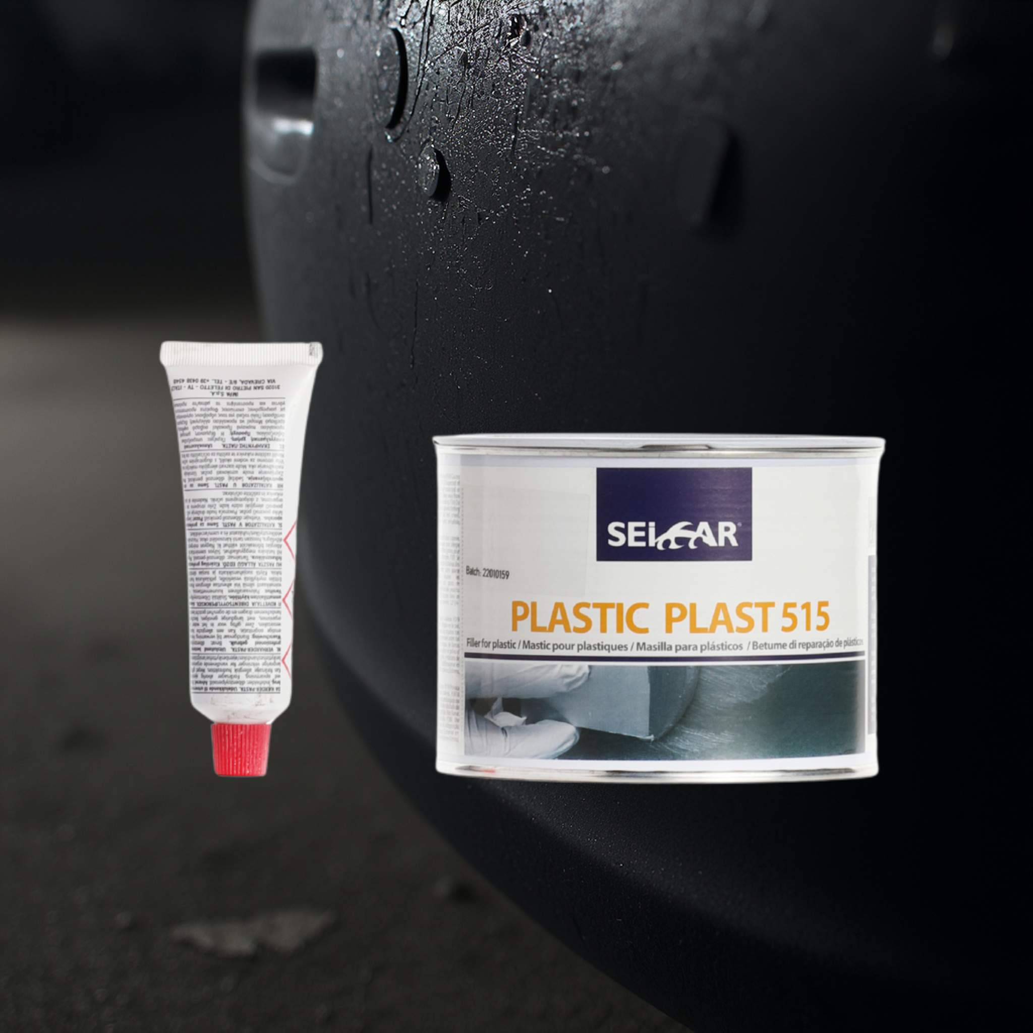 Close-up of a white squeeze tube with a red cap beside a plastic plaster box on a dark surface.